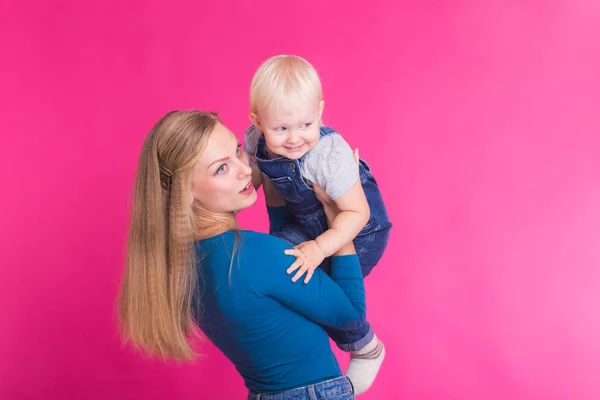 Jovem mãe e filha se divertindo juntos no fundo rosa — Fotografia de Stock