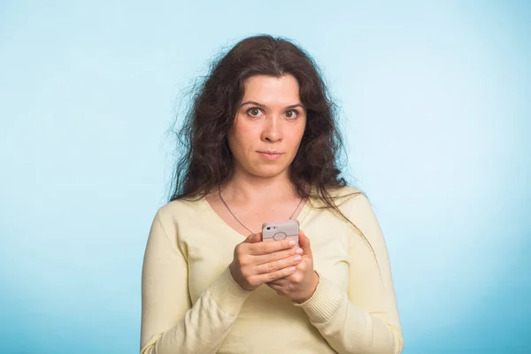 Jovem bela mulher segurando estúdio de telefone móvel no fundo de cor azul . — Fotografia de Stock