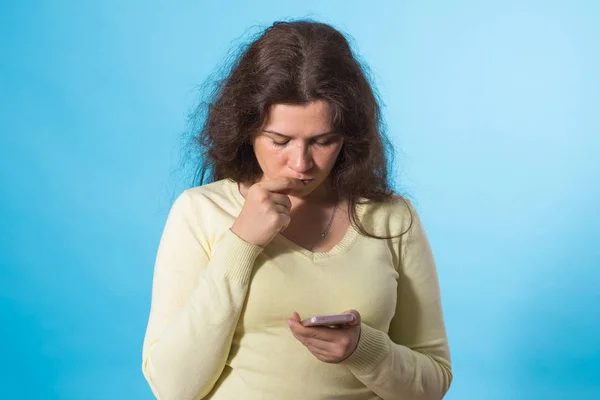 Menina bonita segurando telefone inteligente e enviar sms no fundo azul — Fotografia de Stock