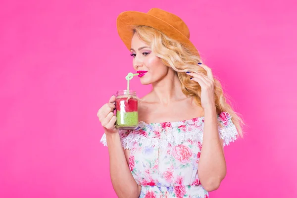 Portret młodej kobiety gospodarstwa i pić milkshake smaczne smoothie zielony na różowym tle z lato — Zdjęcie stockowe