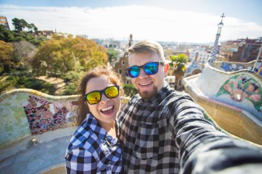 Çift selfie portre ile smartphone Park Guell, Barselona, İspanya, yapım mutlu seyahat. Güzel genç çift kamera ile akıllı telefon aşık gülümseyen fotoğrafı çekmek