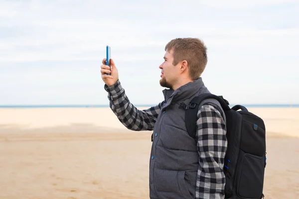 Gezgin adam alarak fotoğraf yaz kamerada smartphone ile plaj tatil seyahat ya da sahile yürüyüş. — Stok fotoğraf