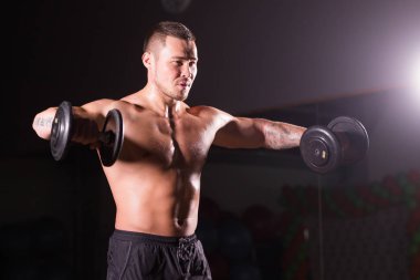 kas genç adam koyu arka plan üzerinde ağırlık kaldırma