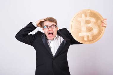 Çığlık atan bir işadamı portresi büyük altın bitcoin kollarında tutar. Adam cryptocurrency kazasında panik içinde