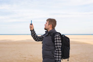 Gezgin adam alarak fotoğraf yaz kamerada smartphone ile plaj tatil seyahat ya da sahile yürüyüş.
