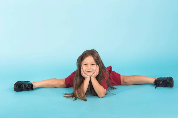 Retrato de linda bailarina haciendo splits aislado sobre fondo azul — Foto de Stock