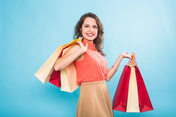 Mujer joven con bolsas de compras sobre fondo azul — Foto de Stock