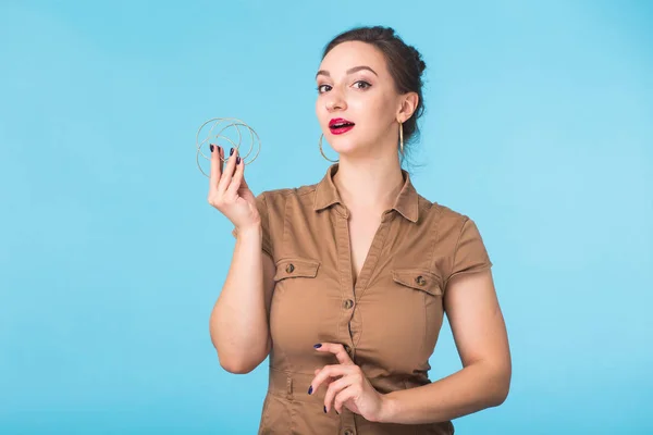 Mujer joven sosteniendo pendientes aislados sobre fondo azul — Foto de Stock