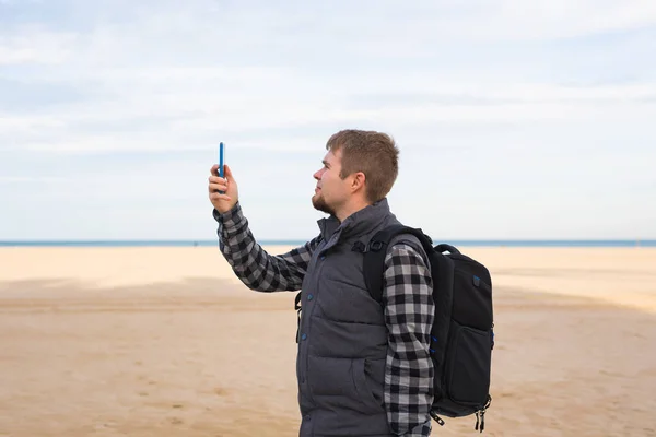 Traveler man taking photos to the beach with smartphone camera on summer travel vacation or hike to the coast. — Stock Photo, Image