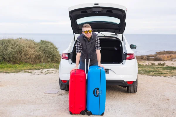 Muž stojící za auto s úsměvem a chystá se jít. Mladí se smíchem mle stojící vedle otevřeného kufru auta. Letní výlet — Stock fotografie