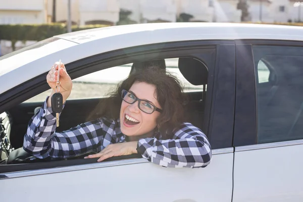 Mladá šťastná žena vyzkoušet řídit nové auto a zobrazení klíč. Koncepce nákup nebo pronájem vozu — Stock fotografie