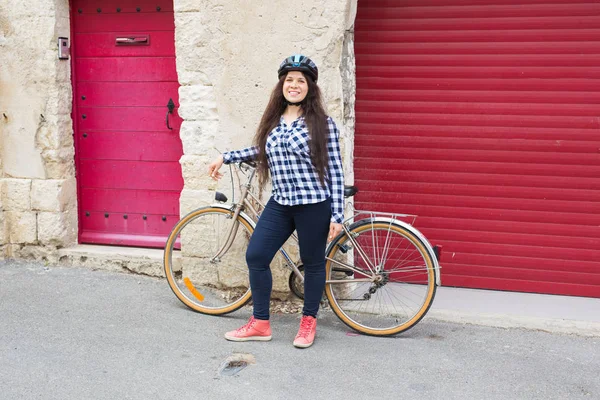빨간 배경 문을 카메라를 찾고 자전거를 젊은 여자 — 스톡 사진