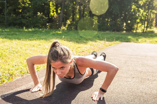 Jeune femme en forme faisant de l'exercice en faisant des pompes à l'extérieur — Photo