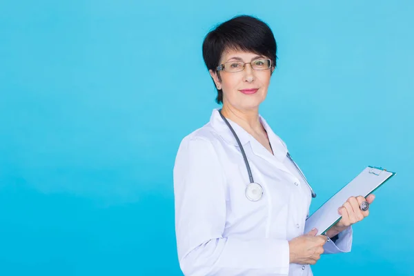 Portret z kobiece kobieta lekarz pisania na Schowka nad niebieskim tle z miejsca kopii — Zdjęcie stockowe