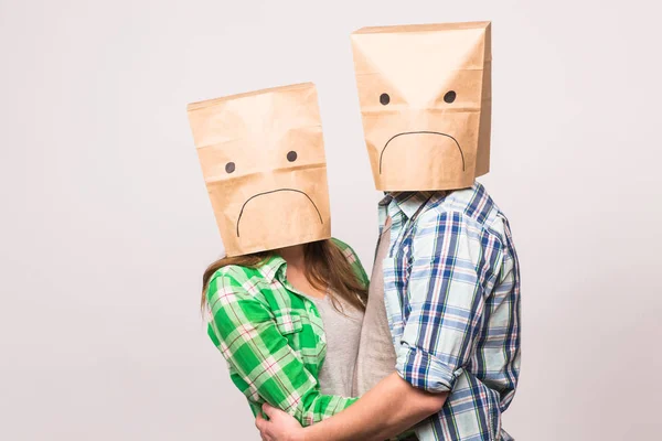 Концепция проблем любви, семьи и отношений - несчастная пара, покрывающая свои грустные лица бумажным пакетом на белом фоне . — стоковое фото