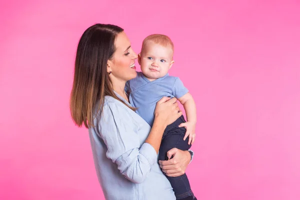 Madre cariñosa jugando con su bebé sobre fondo rosa — Foto de Stock