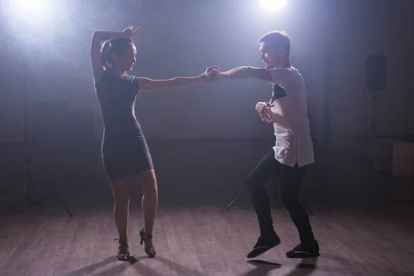 Young couple dancing social danse kizomba or bachata or semba or taraxia in dancing class background