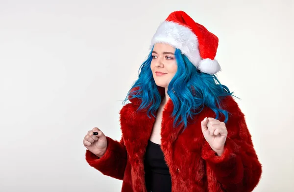 Noel, moda ve gençlik - kırmızı kürklü ve Noel Baba şapkalı güzel genç kadın, kameraya bakıyor ve beyaz arka planda duruyor. Parti için hazır.. — Stok fotoğraf