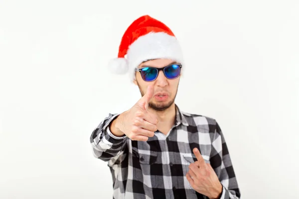 Portrait of a funny young man in Santa Claus hat and beard on white background. Christmas. — Stock Photo, Image