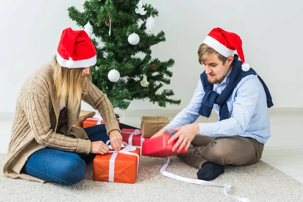 休日のコンセプト – 甘いカップルはクリスマスプレゼントを開き、リビングルームに座って — ストック写真