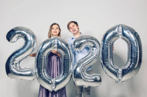 New year, celebration and holidays concept - love couple having fun with sign 2020 made of silver balloons for new year