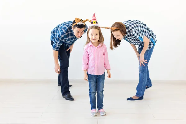 Concepto de vacaciones de invierno: familia navideña con cuernos de Santa Sombrero y ciervo. Celebración familiar sonriente —  Fotos de Stock