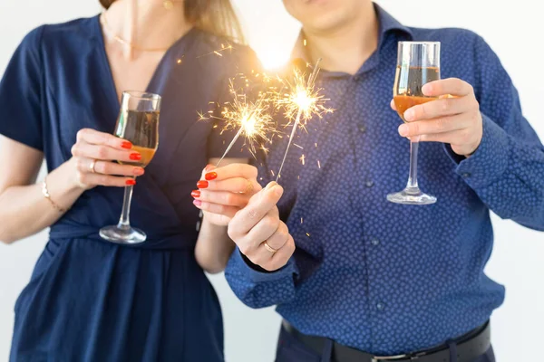 Close-up van man en vrouw die Kerstmis of oudejaarsavond feest vieren met Bengaalse lichten en glazen champagne. — Stockfoto