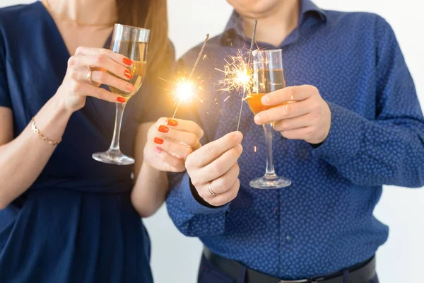 Close-up van man en vrouw die Kerstmis of oudejaarsavond feest vieren met Bengaalse lichten en glazen champagne. — Stockfoto