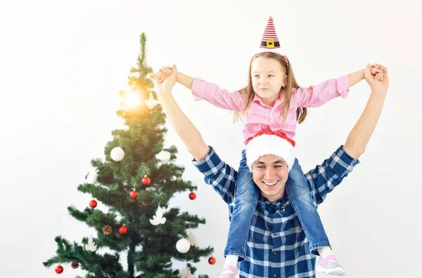 Portrait of happy father piggybacking child during Christmas at home