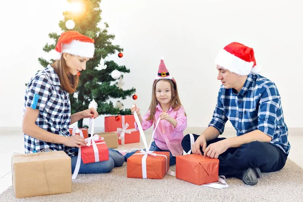 Vánoční a prázdninový koncept - Rodinné otevírání vánočních dárků před stromem — Stock fotografie
