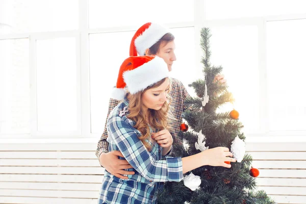 Famiglia, x-mas, vacanze invernali e concetto di persone - felice giovane coppia decorazione albero di Natale a casa — Foto Stock