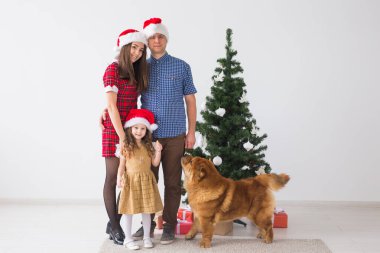 Evcil hayvan, tatil ve festival konsepti. Köpekli aile Noel ağacının yanında duruyor..