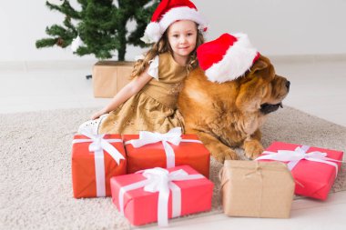 Çocuklar ve evcil hayvan konsepti. Noel ağacının yanında oturan köpekli tatlı kız. Mutlu Noeller ve mutlu tatiller.