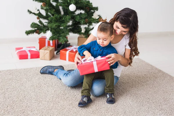 Boże Narodzenie, samotny rodzic i koncepcja święta - Cute little boy gospodarstwa Boże Narodzenie prezent dla matki w domu. — Zdjęcie stockowe