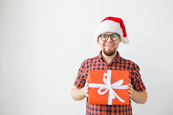 Concepto de Navidad y vacaciones - Hombre divertido en sombrero de santa celebración de un regalo sobre fondo blanco con copyspace — Foto de Stock