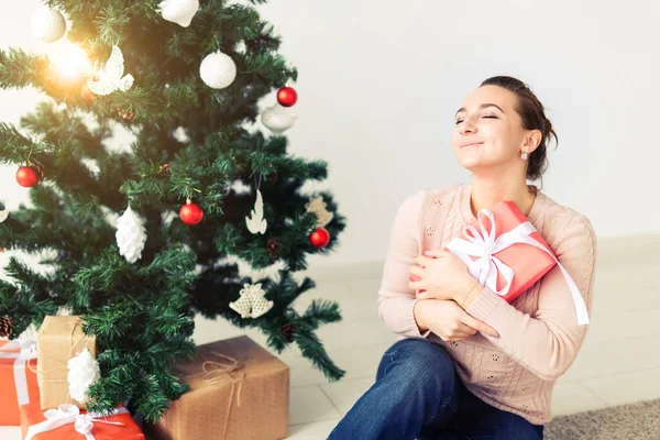 Christmas, x-mas, winter, happiness concept - girl opens a gift against the background of the Christmas tree. Happy young woman celebrating Christmas — Φωτογραφία Αρχείου