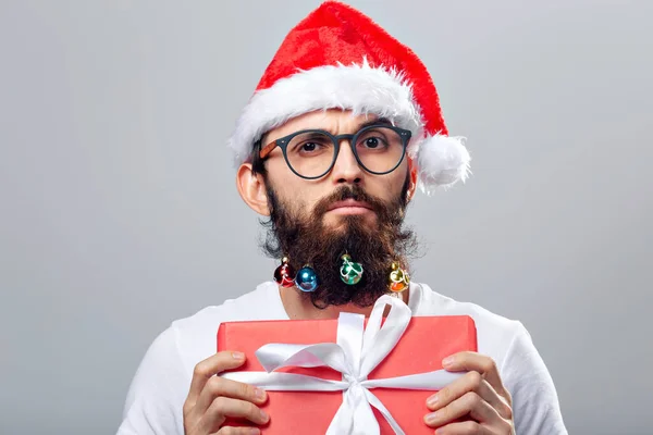 Natale, vacanze, barbiere e concetto di stile - giovane Babbo Natale barbuto uomo con molte piccole bagattelle di Natale in lunga barba — Foto Stock