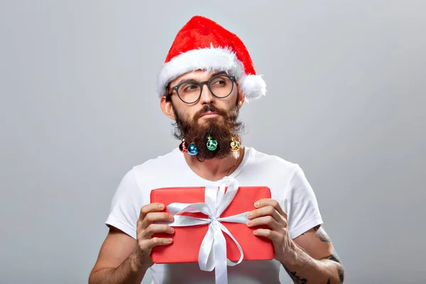 Christmas, holidays, barbershop and style concept - young handsome bearded santa claus man with many small christmas baubles in long beard — Zdjęcie stockowe