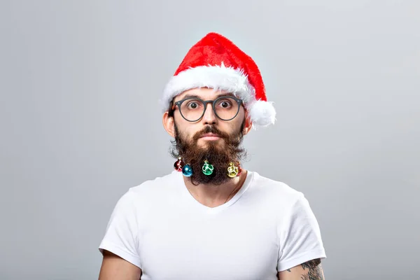 Christmas, holidays, barbershop and style concept - young handsome bearded santa claus man with many small christmas baubles in long beard — Stockfoto