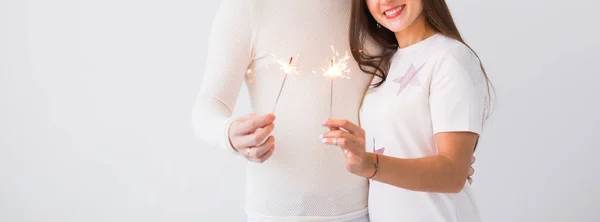 Romantisches schönes Paar beim Date am Valentinstag. Mann und Frau halten Wunderkerzen auf weißem Hintergrund mit Copyspace — Stockfoto