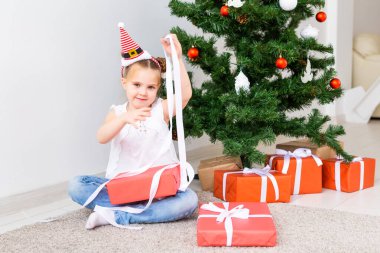 Çocuk Noel hediyelerini açıyor. Noel ağacının altında hediye kutularıyla çocuk.