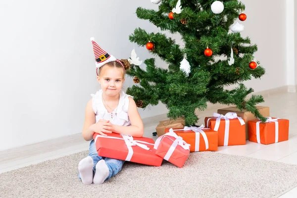 Regali di Natale per l'apertura dei bambini. Bambino sotto l'albero di Natale con scatole regalo . — Foto Stock