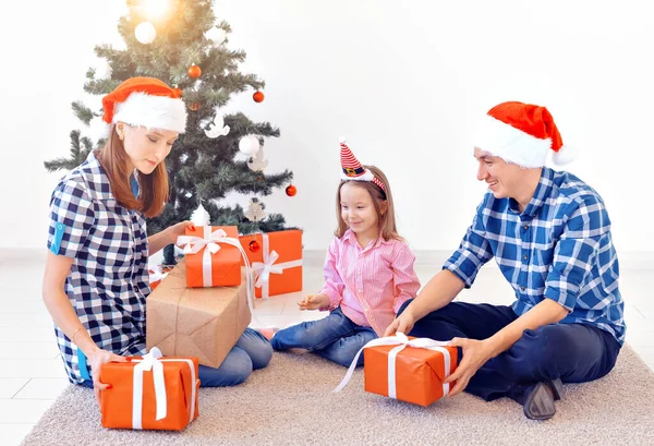 X-mas y el concepto de vacaciones - Apertura de la familia de Navidad presente delante del árbol — Foto de Stock