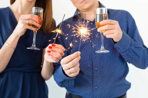 Close-up de homem e mulher comemorando a festa de Natal ou Ano Novo com luzes de Bengala e copos de champanhe . — Fotografia de Stock