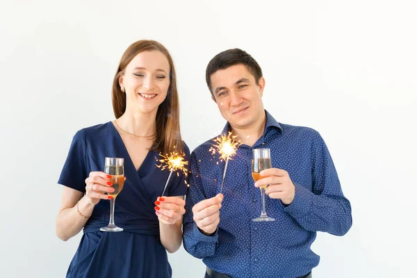 Homem e mulher comemorando a festa de Natal ou Ano Novo com luzes de Bengala e copos de champanhe no fundo branco . — Fotografia de Stock