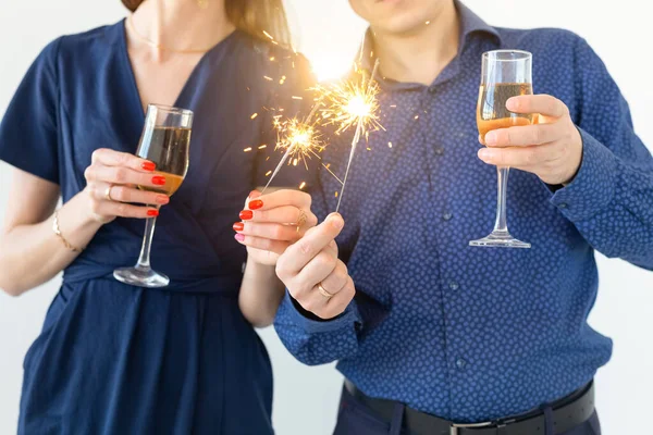 Close-up de homem e mulher comemorando a festa de Natal ou Ano Novo com luzes de Bengala e copos de champanhe . — Fotografia de Stock