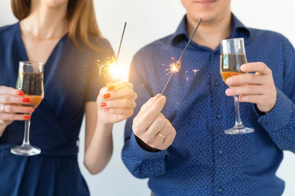 Крупный план мужчины и женщины празднуют Рождество или Новый год бенгальскими огнями и бокалами шампанского . — стоковое фото