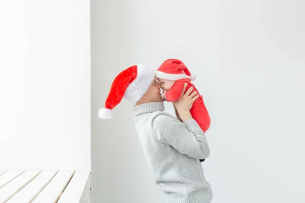 Concetto di paternità e vacanze - Padre con il suo bambino che indossa i cappelli di Babbo Natale per festeggiare il Natale — Foto Stock