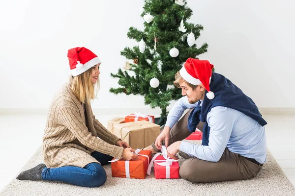 休日のコンセプト – 甘いカップルはクリスマスプレゼントを開き、リビングルームに座って — ストック写真