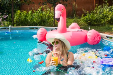 Çöp sorunu, plastik geri dönüşüm, kirlilik ve çevre kavramı - aptal kadın yüzer ve kirli bir havuzda eğlenin. Şişeler ve plastik torbalar onun yanında yüzer.